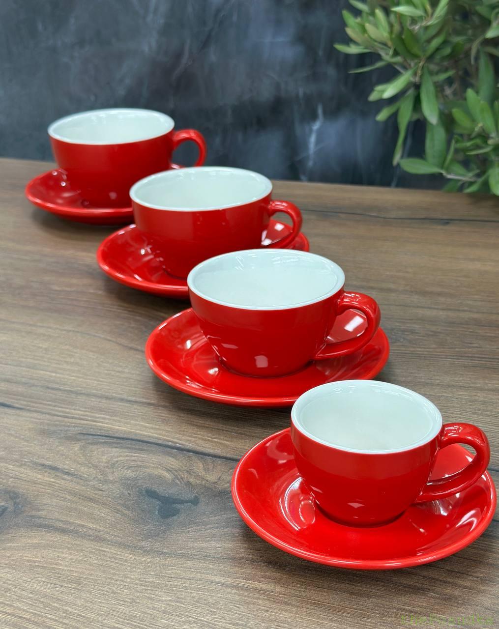 Glossy red cups with white interiors on red saucers