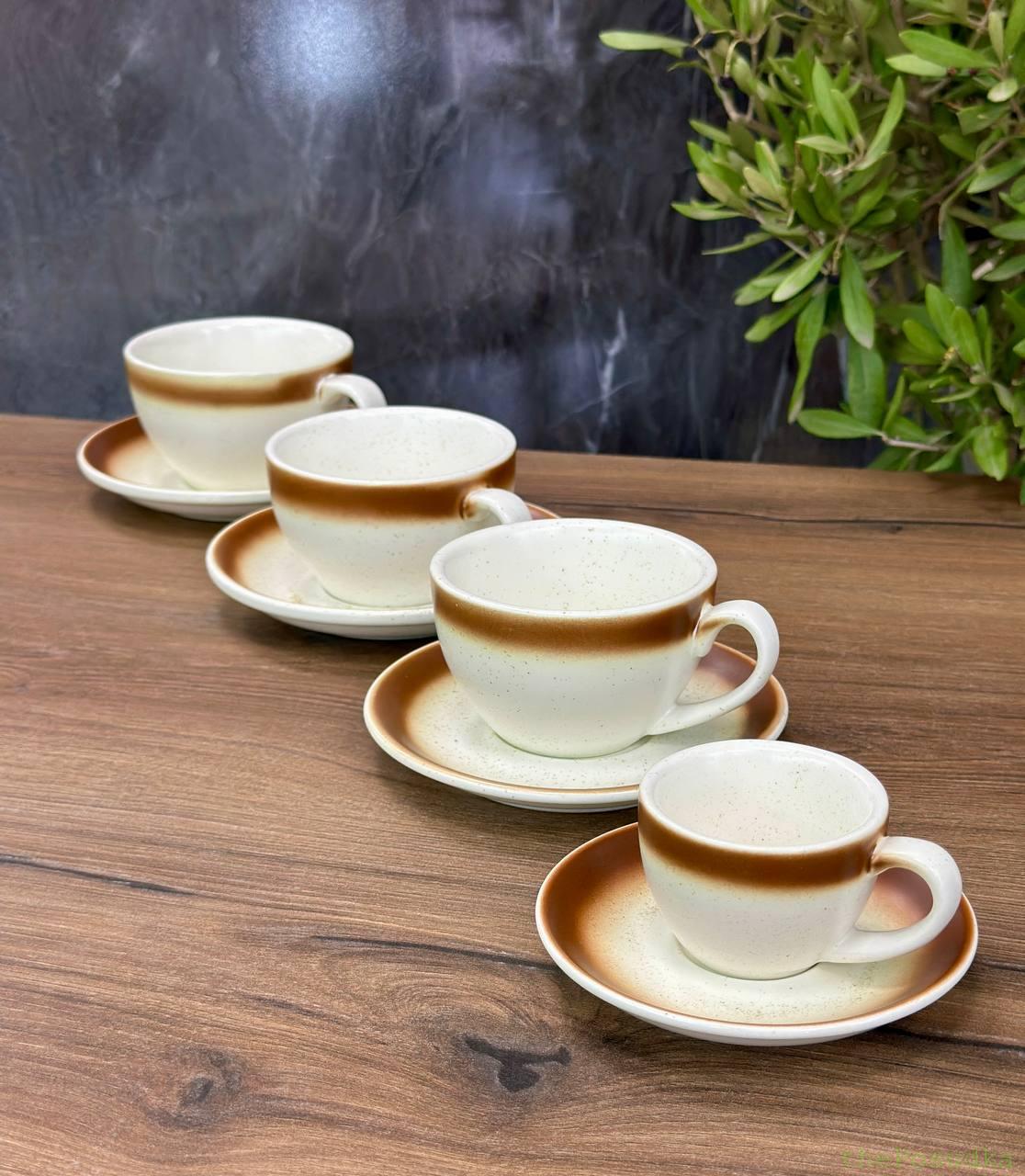 Matte black cups with reactive blue-glazed interiors and saucers