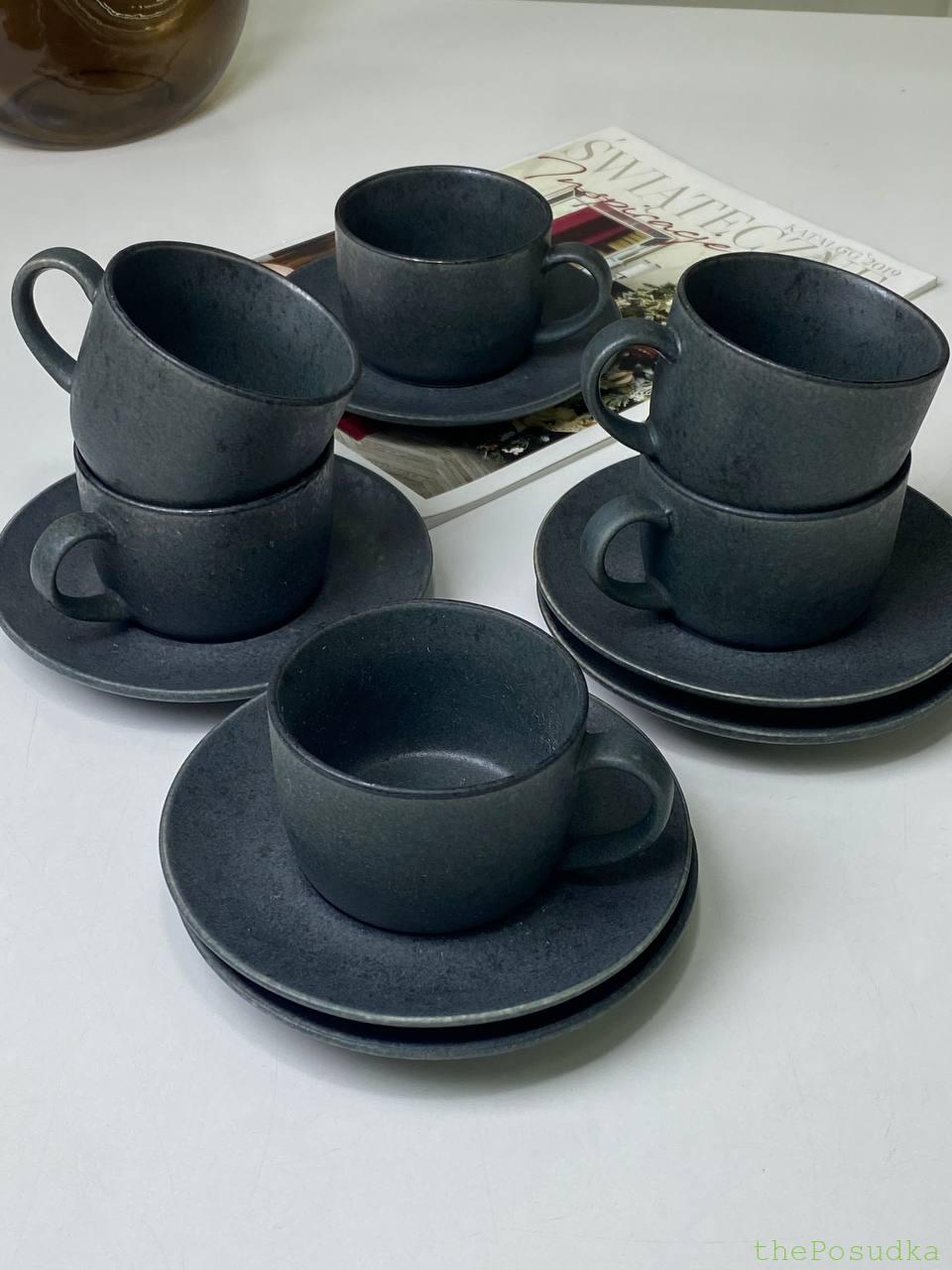 Black cups with white speckled glaze and matching saucers